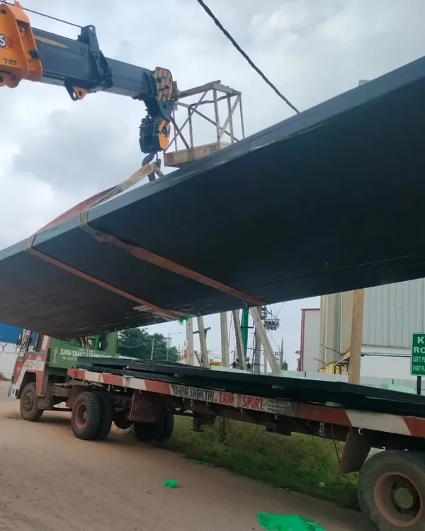 A large, prefabricated panel for the Tiruppur Business Hub is lifted into place. These panels are made from recycled PET bottles, making them lightweight, sustainable, and allowing for rapid on-site assembly.