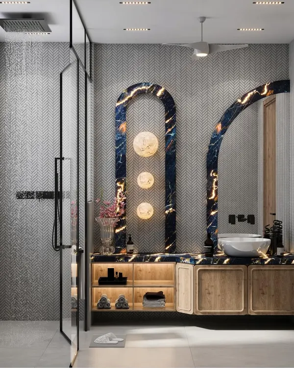 This washroom blends calm tones with striking details. A deep blue backlit marble panel serves as a bold visual anchor, while warm wooden cabinetry and chevron tiles create a serene, elegant experience.