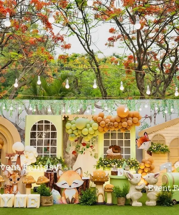 A breathtaking, wide-angle view of Ryne's woodland party. The entire setup is framed by beautiful flowering trees, featuring a charming house backdrop, 3D animal cutouts, and whimsical props for a complete fantasy world.