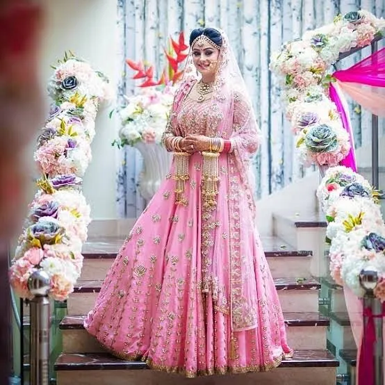 A beautiful bride in a custom-stitched pink lehenga we designed for her special day. We work with you to create the perfect wedding outfit that matches your vision and ensures you look your best.