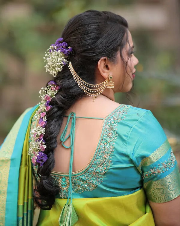 A stunning Marathi bridal hairstyle. This intricate braid is adorned with fresh purple and white flowers and a traditional hair accessory, creating a look of pure elegance.