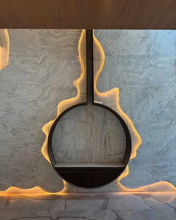 A close-up of a bespoke fireplace feature where we carved into a stone wall and used backlighting to create a fluid, glowing outline. This detail transforms a functional element into a central art piece.