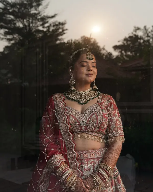 A moment of serene beauty before the ceremonies begin. We gave this bride a radiant, flawless finish with a soft focus on the eyes, perfectly complementing her intricate red and pink lehenga.