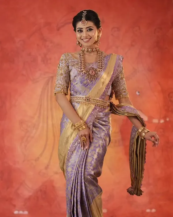 A model looking regal in a lavender silk saree, paired with a custom blouse featuring heavy gold embroidery on the sleeves.