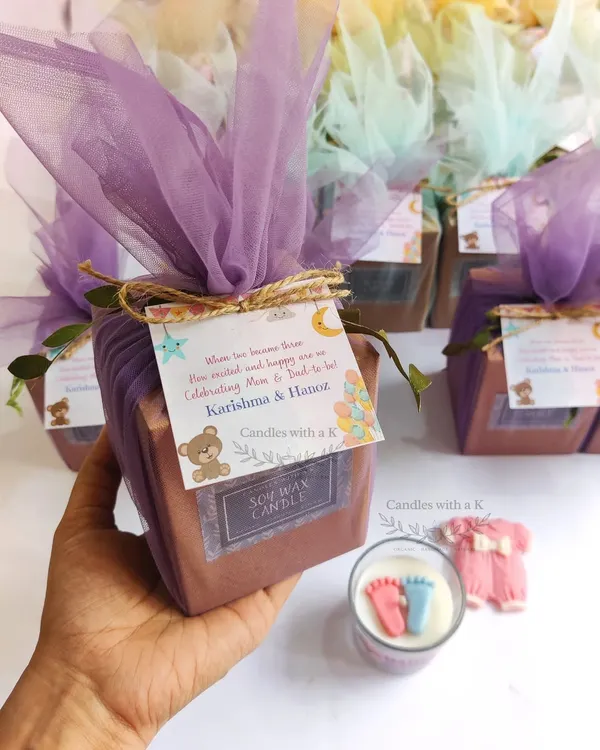 A complete gift set for Karishma's baby shower, featuring a votive candle with tiny baby feet and a baby onesie wax sachet, all wrapped in a beautiful teddy bear theme.