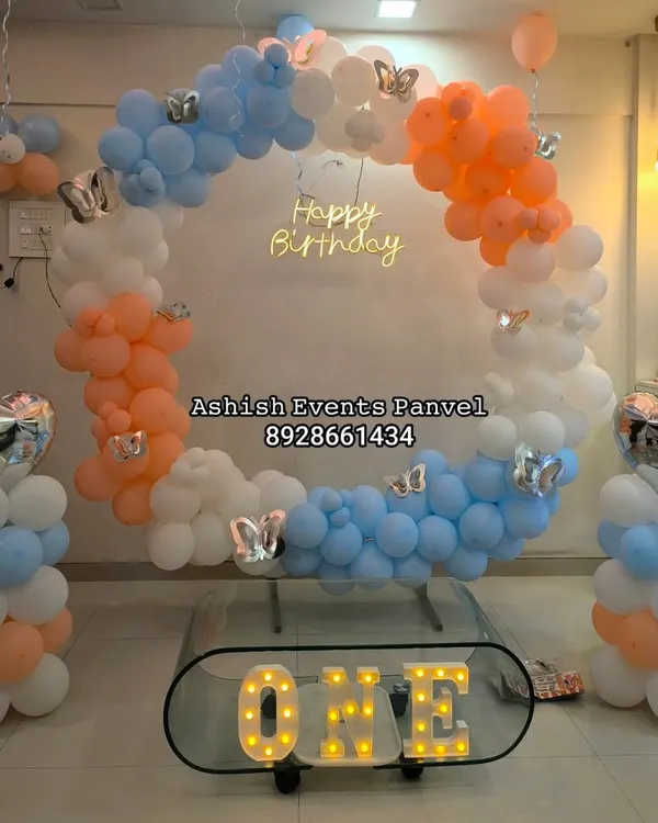 This modern ring-shaped balloon backdrop with a 'Happy Birthday' neon sign is perfect for a stylish first birthday. The 'ONE' marquee letters add a special touch.