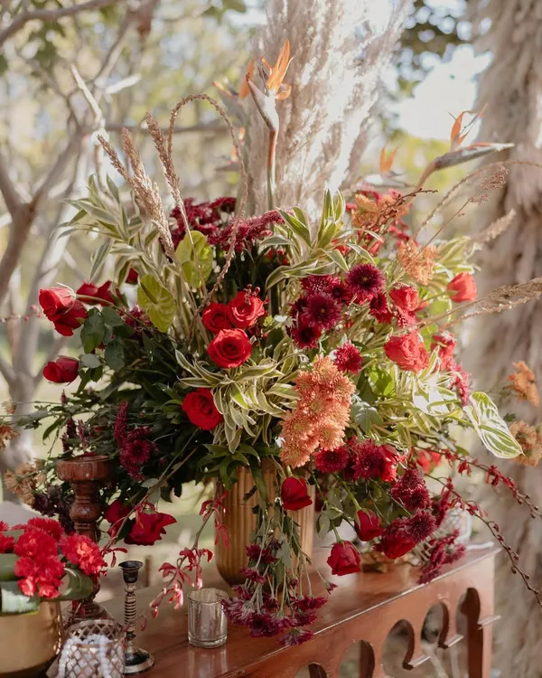 A lush floral arrangement from our 'Regal Rustic Reverie' wedding. The combination of deep red roses, birds of paradise, and other exotic greens created a look that was both dramatic and incredibly elegant.