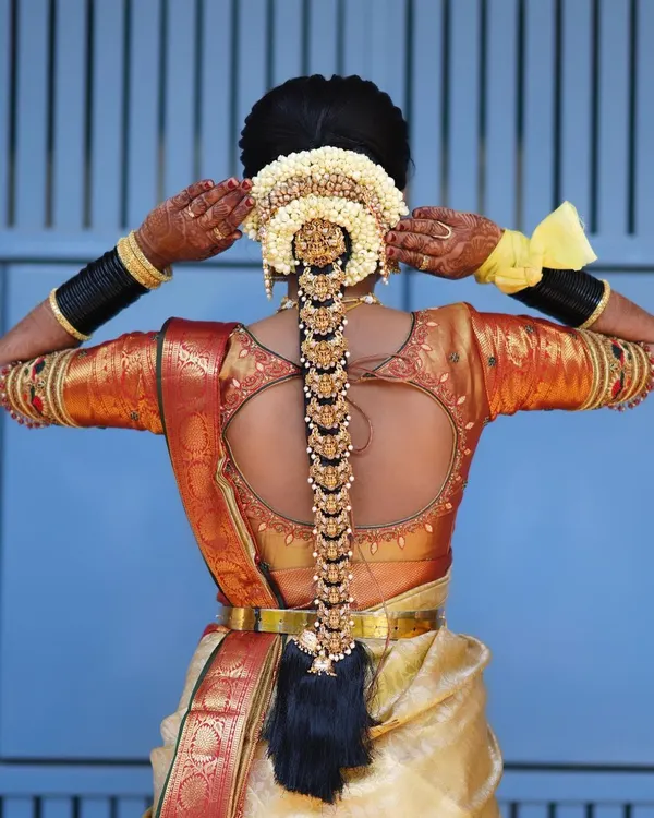 This is the quintessential South Indian muhurtham look. I created a thick, neat braid and adorned it with traditional gold-plated temple jewellery, known as jada billai, and a jasmine gajra for a timeless and grand bridal hairstyle.