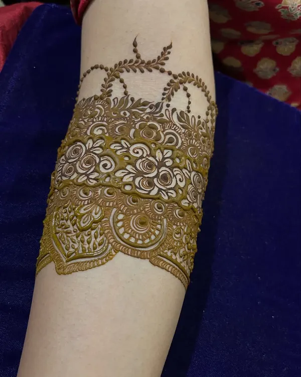 A bridal Indian arm band design with delicate hanging chains and intricate floral patterns.