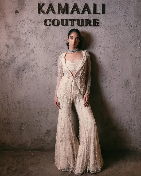 An exquisite blend of tradition and modernity, this ivory sharara set is a masterpiece of intricate craftsmanship. It features a structured, embellished blazer, a coordinating bustier, and flowing sharara pants.