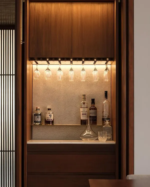 This custom-designed bar unit for our Altamount Road apartment is a perfect example of integrated design. The warm, concealed LED lighting highlights the textured backdrop and glassware, while the rich wood cabinetry provides seamless, elegant storage.