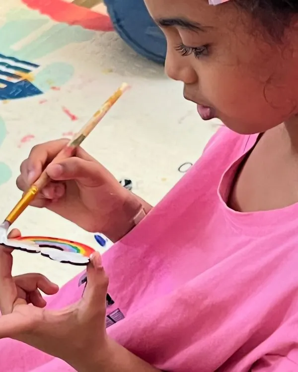 A close-up from a fun-filled birthday party! This little artist is adding the final touches to her rainbow cutout. Our art activities are a perfect, engaging addition to any celebration.