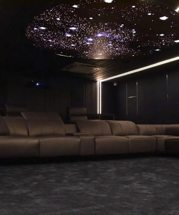 A view of a completed custom home cinema featuring luxury recliner seating and a starlit ceiling. This setup is designed for ultimate comfort and immersion, making it the perfect private screening room.