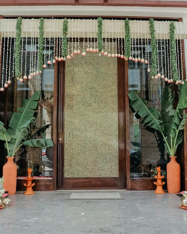 A beautiful and traditional entrance for a housewarming ceremony. We used garlands of jasmine and lotus buds, large banana plants in terracotta vases, and brass diyas to create a truly auspicious welcome.