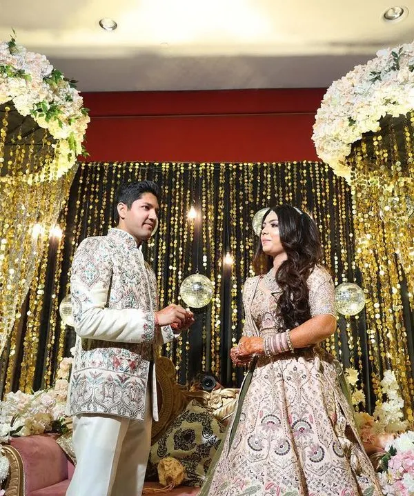 A glamorous engagement stage featuring a backdrop of cascading gold sequins and elegant white floral arches. This design creates a dazzling, celebratory atmosphere perfect for the ring ceremony.
