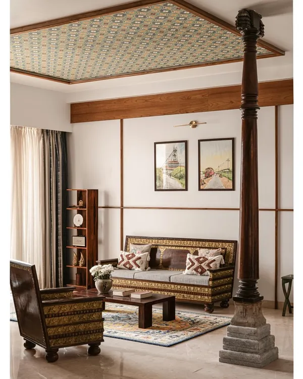 We designed this living room around the family's antique furniture, letting its history be the anchor. A Chettinad pillar adds structural grace, while the wallpapered ceiling brings a layer of subtle pattern to the space.