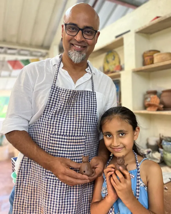 A father and daughter duo beaming with pride as they hold up the small clay figures they made together. These sessions are all about creating shared memories.