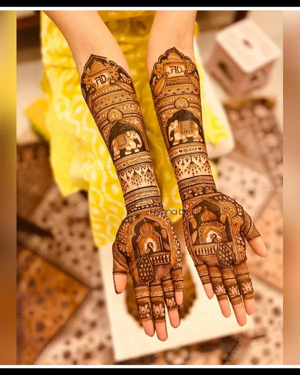 A beautiful engagement mehendi design reaching up to the forearms. This piece features personalized initials, majestic elephants, and traditional jharokha patterns, telling a unique story for the bride-to-be.