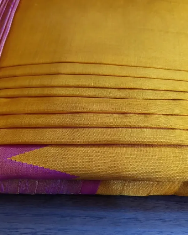 A close-up of a client's yellow and pink silk saree after my pre-pleating and box folding service.