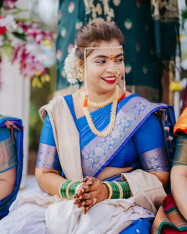 A lovely candid portrait of a bride in a royal blue saree, smiling during her Maharashtrian wedding ceremony.