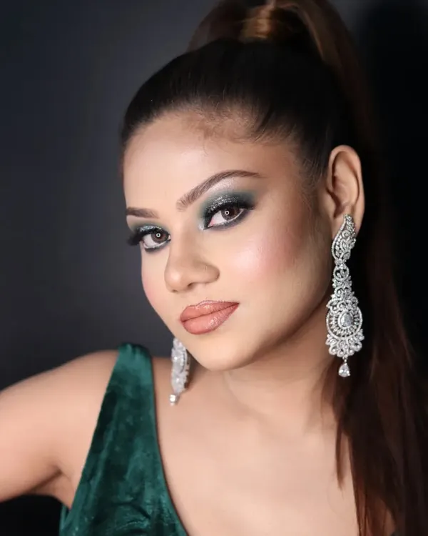 A stunning cocktail makeup look with dramatic green smokey eyes, a flawless base, and a high ponytail.