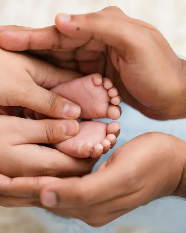 A classic and powerful shot of a newborn's tiny feet being held safely in their parents' hands.
