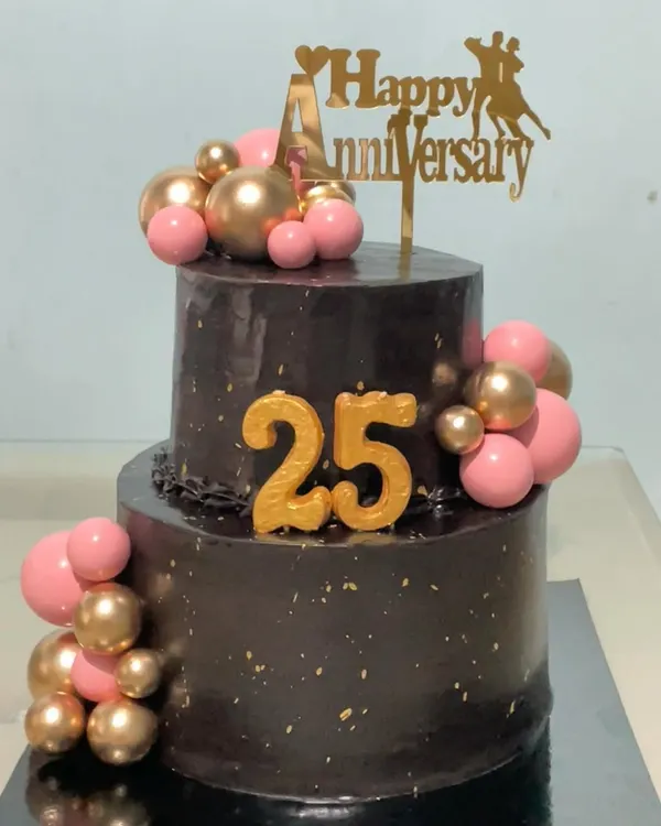 Celebrating a silver jubilee with this stunning two-tiered chocolate truffle cake. The rich chocolate base is decorated with pink and gold spheres and a "Happy 25th Anniversary" topper for a truly special milestone.