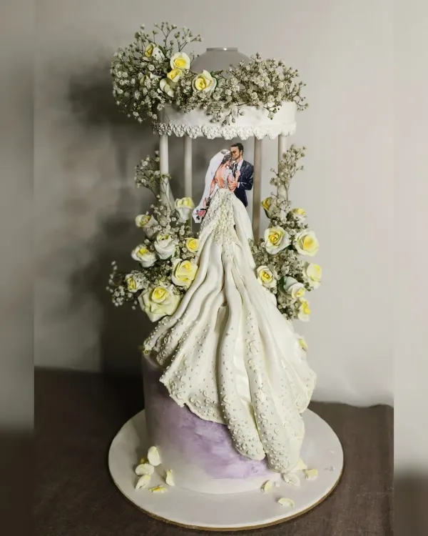 This wedding cake was a true showstopper. The design features a bride's gown flowing down the side of the cake, complete with intricate textures and sparkle. Housed within a delicate birdcage structure and adorned with fresh baby's breath, it's a cake that tells a romantic story.