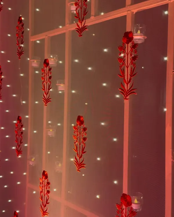 Simplicity in details. Red laser-cut floral motifs and tea lights create a delicate, heritage-inspired backdrop for a sangeet night.