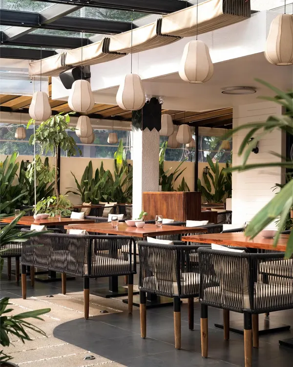 I believe a restaurant should feel like an escape. For this heritage bungalow project, I designed an outdoor seating area with a retractable pergola, lush greenery, and custom banana fiber lights to create a refreshing, tropical ambiance day and night.