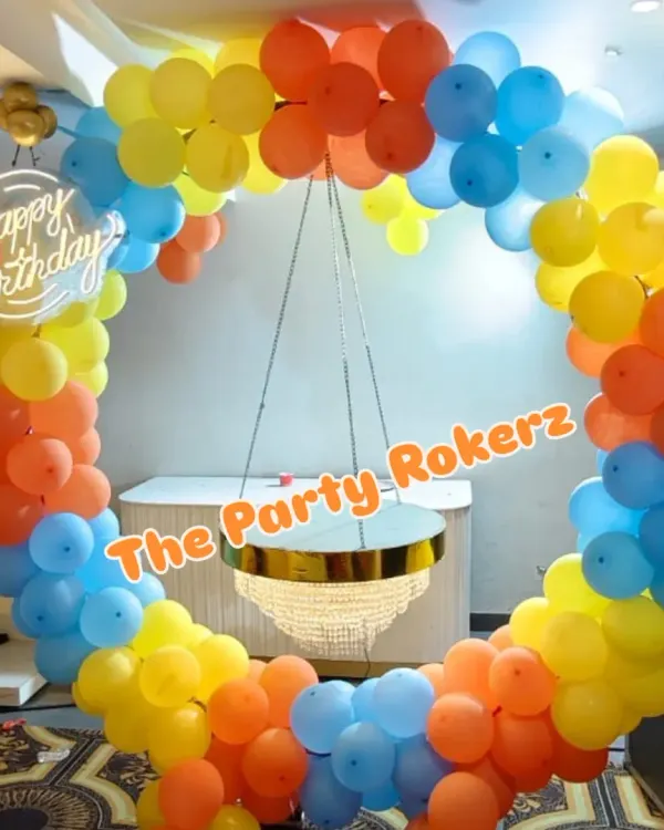 A colorful balloon ring with a hanging chandelier-style cake table. This is a unique and elegant way to display the birthday cake and serves as a fantastic photo backdrop.