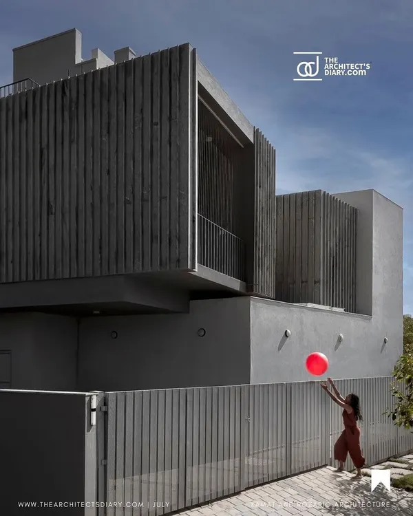 The facade of 'Maya House' is defined by its clean lines and the texture of the vertical Sadarhalli stone fins. This material choice is not just aesthetic; it helps regulate the light entering the south-facing home.