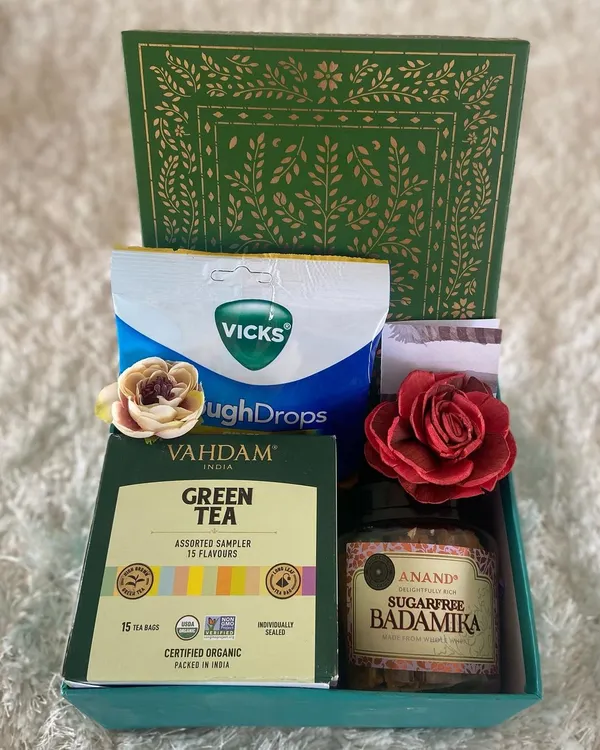 When someone you care about is feeling under the weather, a thoughtful care package can make all the difference. This simple yet effective get well soon hamper includes Vahdam green tea, sugar-free Badamika sweets, and Vicks cough drops.