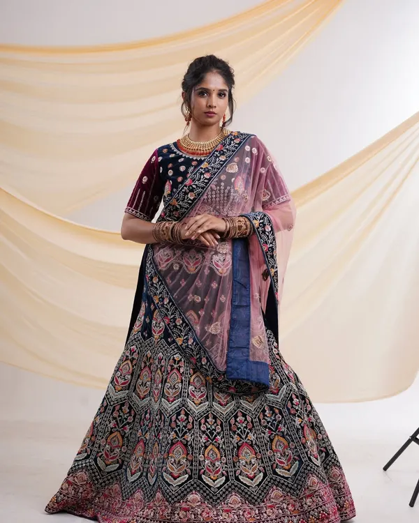 A breathtaking navy blue velvet lehenga with intricate multi-color embroidery and a contrasting pink dupatta. This is a perfect choice for a bride or for attending a wedding.