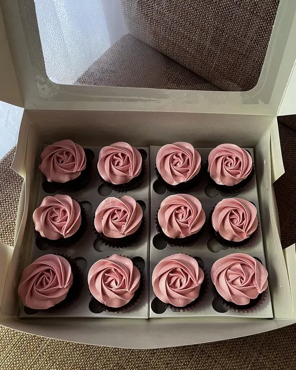 A box of my classic chocolate cupcakes with a pretty pink whipped cream frosting. I pipe each rosette by hand, making them a beautiful and delicious choice for parties, gifts, or just because.