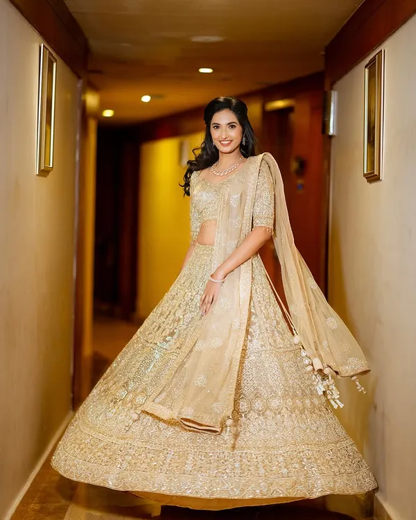 A full-length portrait of the bride, Shalmali, twirling in her gorgeous golden lehenga.