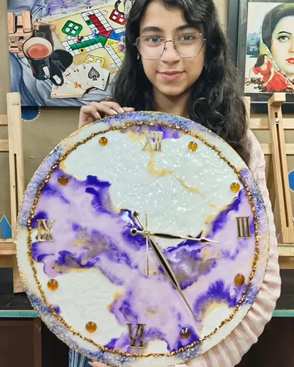 A talented student showcasing her magnificent resin art clock. Our workshops guide you through the entire process, from mixing colors to adding details like clock hands and numbers.