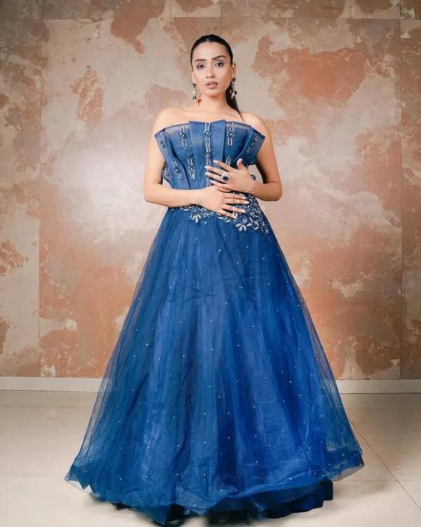 A classic portrait of elegance in a stunning royal blue ball gown. The studio lighting is crafted to highlight the texture of the denim-style corset and the shimmering tulle skirt, creating a look of modern royalty.