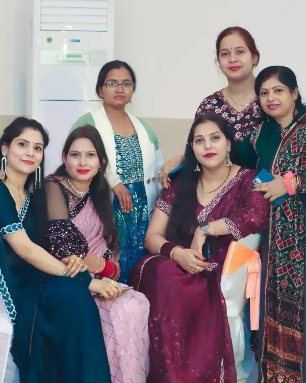 A group of female guests dressed in elegant sarees and suits posing together at a party.