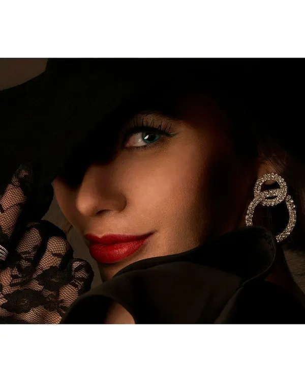 A classic, glamorous look for a jewellery shoot, focusing on the model's elegant pose and the sparkle of the diamond earrings. The dramatic, low-key lighting creates a sense of mystery and sophistication.