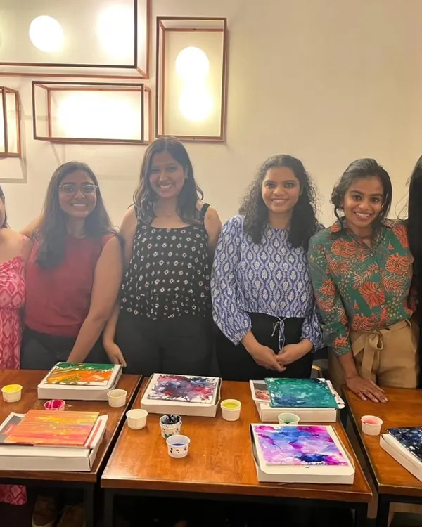 A group of friends proudly displaying their colorful fluid art canvases. Our paint and sip events are a great way to catch up while creating something beautiful and abstract.