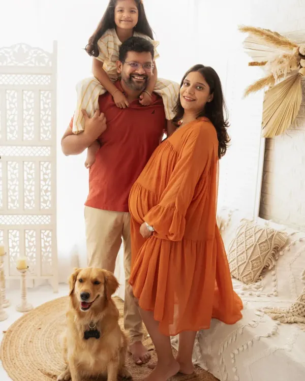 A fun and joyful family portrait. With the older sibling on dad's shoulders and the family dog by their side, this photo is full of life and happiness.