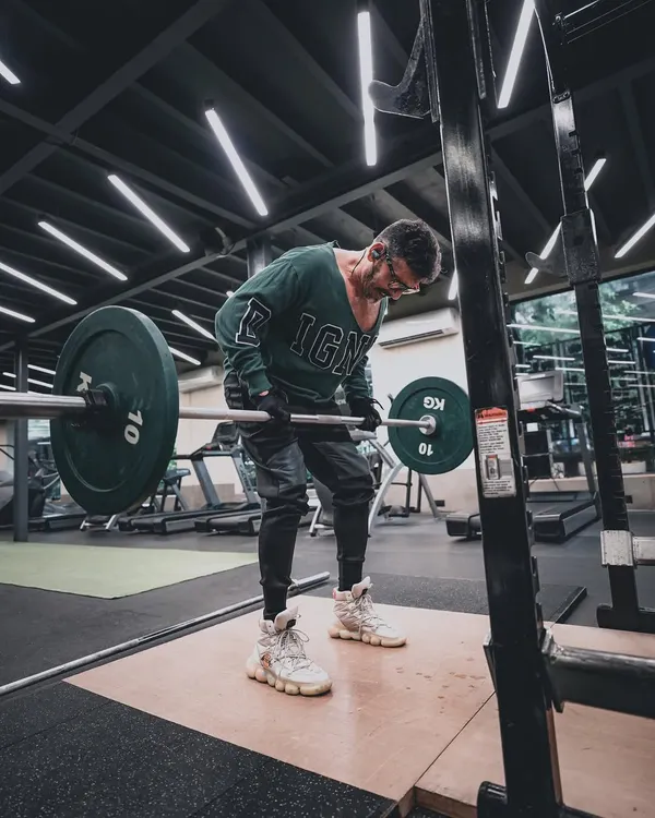 Capturing the grind of a workout. This fitness lifestyle shot focuses on the subject's form during a barbell row, using the gym's ambient lighting to create a raw, motivational atmosphere.