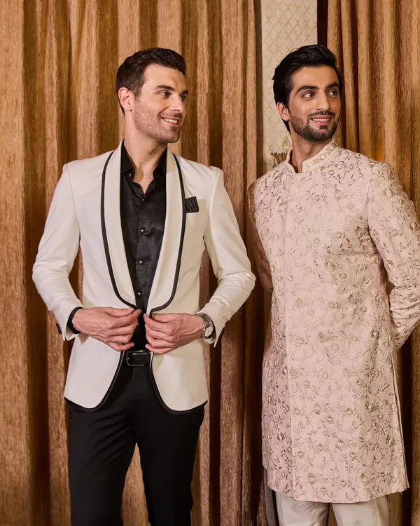 Showcasing the versatility of my collections, this image pairs a classic white tuxedo with a contemporary embroidered Indo-Western sherwani. Whether your style is ethnic or western, I can create a coordinated look for you and your groom squad.