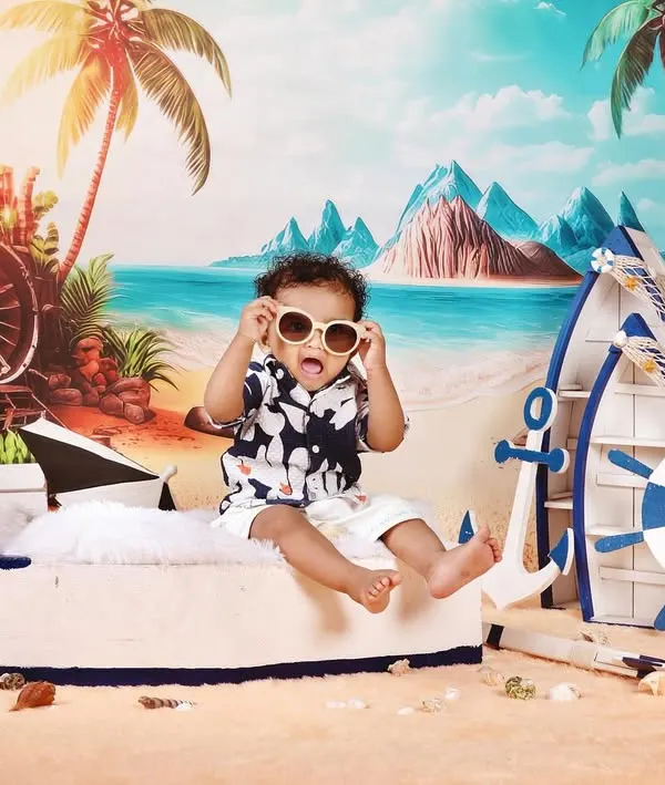 Fun and creative themed photoshoots are one of my specialties. For this pre-birthday session, we created a vibrant beach scene right in the studio, complete with a boat, sand, and sunglasses for little Naksha to enjoy. These shoots are all about capturing your child's personality.