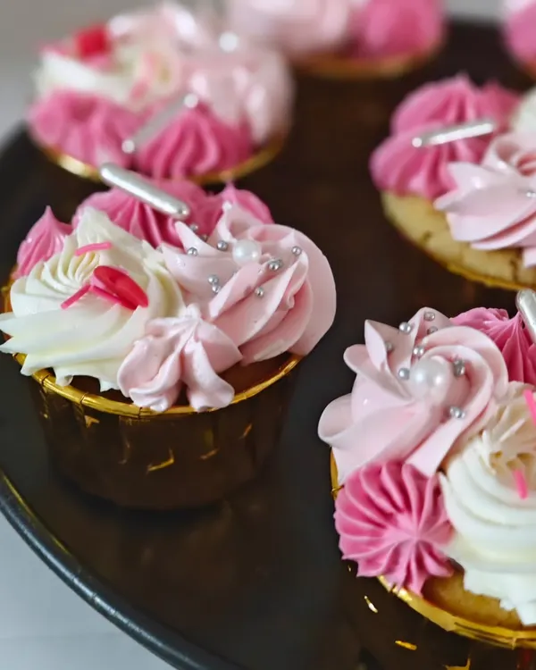 A close-up of my vanilla cupcakes with strawberry buttercream, decorated with delicate piping and silver sprinkles.