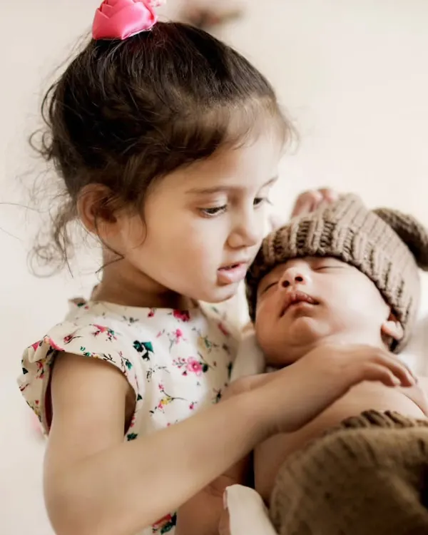 A tender moment between an older sister and her sleeping newborn brother. Capturing the start of a lifelong sibling bond is one of my favorite things.