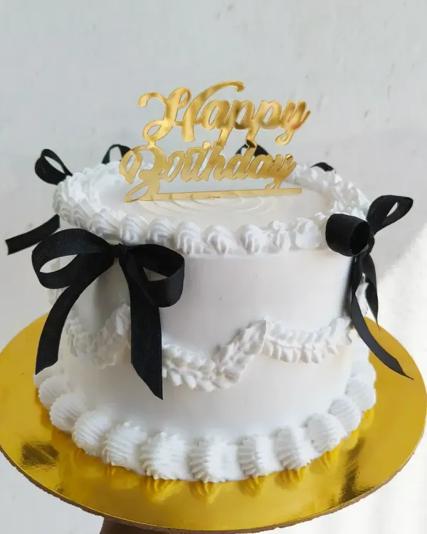 A beautiful vintage-style cake with delicate white piping and black ribbons. This classic and elegant design is perfect for any celebration.