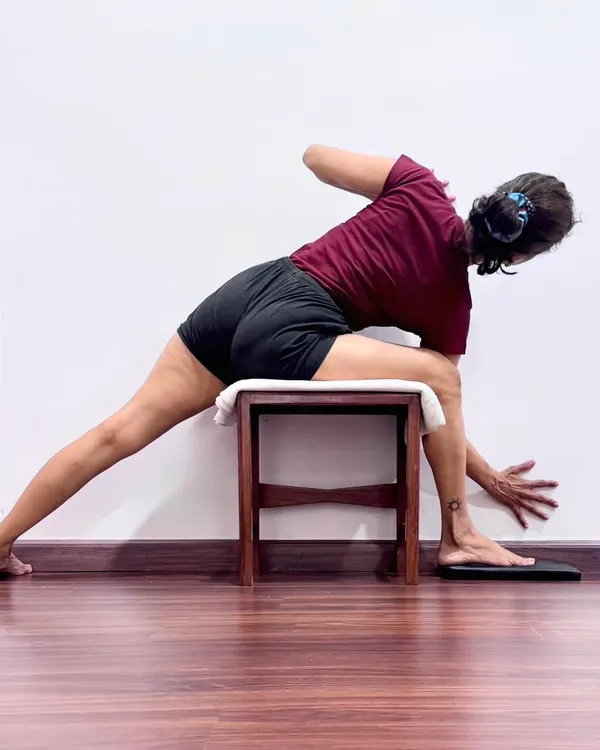 Using a stool in Parivrtta Trikonasana helps establish a firm foundation. As Guruji taught, when the base is correct, the asana is correct. This prop allows the student to focus on the spinal twist and horizontal extension of the chest, teaching the body stability and balance.