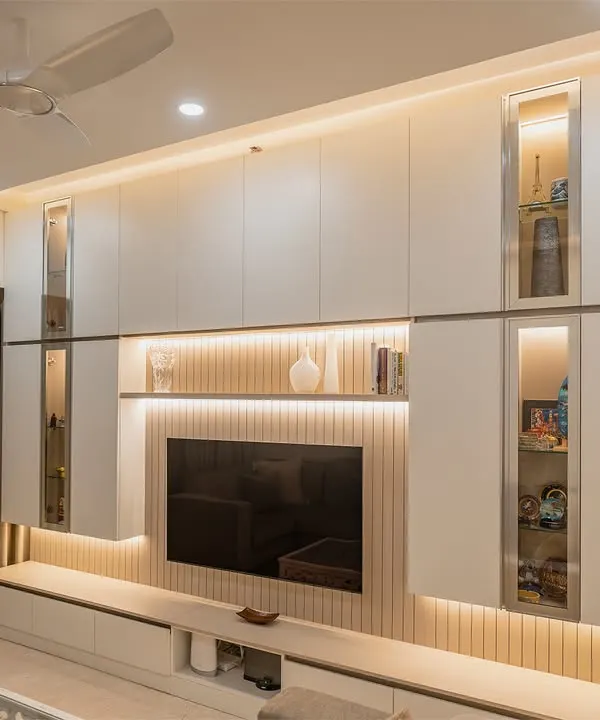 This full-wall entertainment unit is a masterpiece of functional design. It features a mix of closed cabinets, open shelves, and glass display sections, all beautifully illuminated with integrated LED lighting.